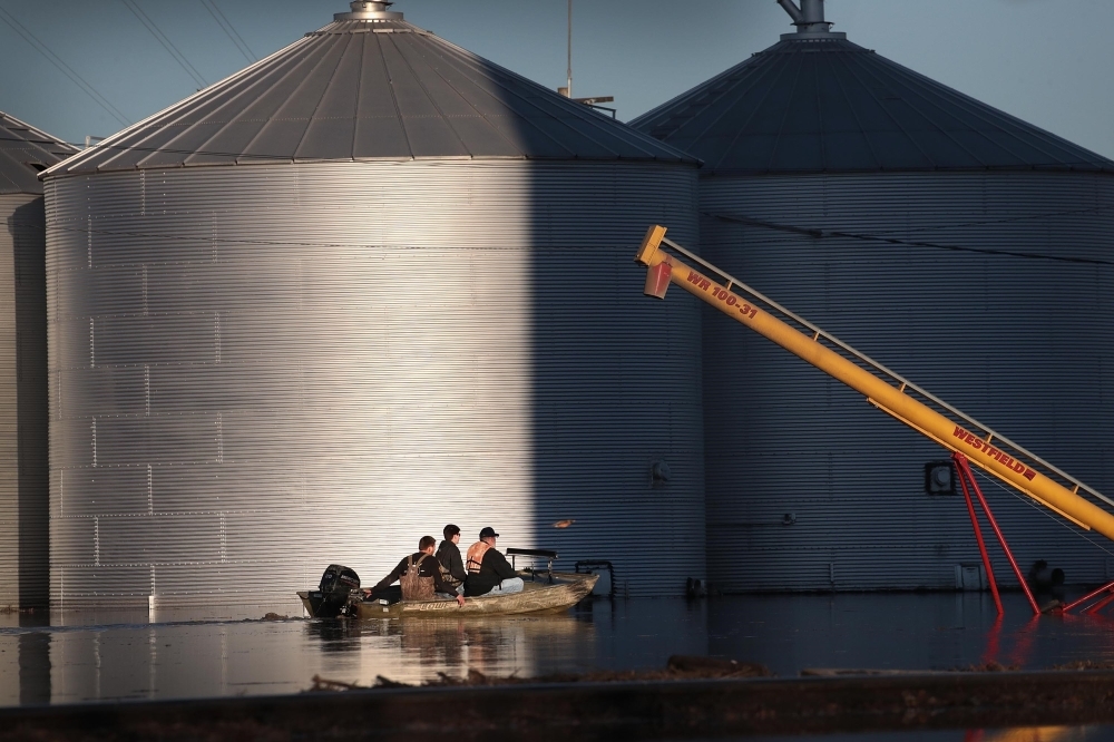 A boat passes by grain bins which are surrounded by floodwater in Craig, Missouri, on Thursday. — AFP