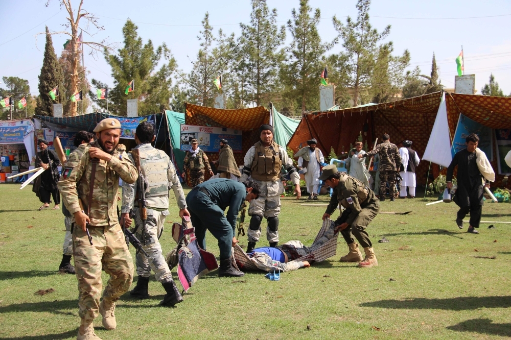 Afghan security personnel carry a victim following twin explosions in Lashkar Gah, the capital of Helmand province, Saturday. At least three people were killed and 30 wounded in twin explosions inside a stadium hosting an agricultural show in southern Afghanistan, officials said. — AFP