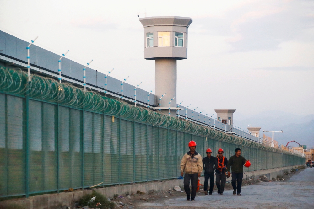 Workers walk by the perimeter fence of what is officially known as a vocational skills education center in Dabancheng in Xinjiang Uighur Autonomous Region, China, in this Sept. 4, 2018 file photo. — Reuters