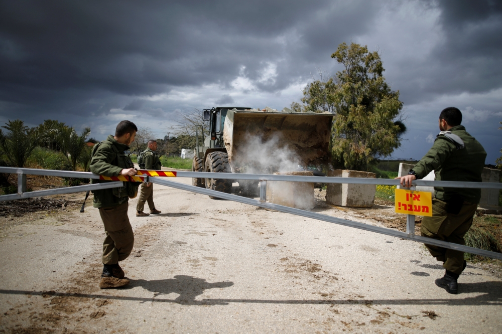 Israeli soldiers watch as a military armored bulldozer moves concrete barricade blocks to close a road near the border with Gaza, in southern Israel, Monday. — Reuters