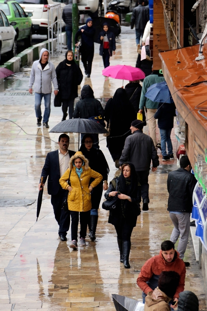 


Iranians carry umbrellas on a rainy day in Tehran. Major floods across much of Iran have left 21 people dead and more than 100 injured, blocking roads and triggering landslides with warnings of more heavy rain to come, emergency services said. — AFP
