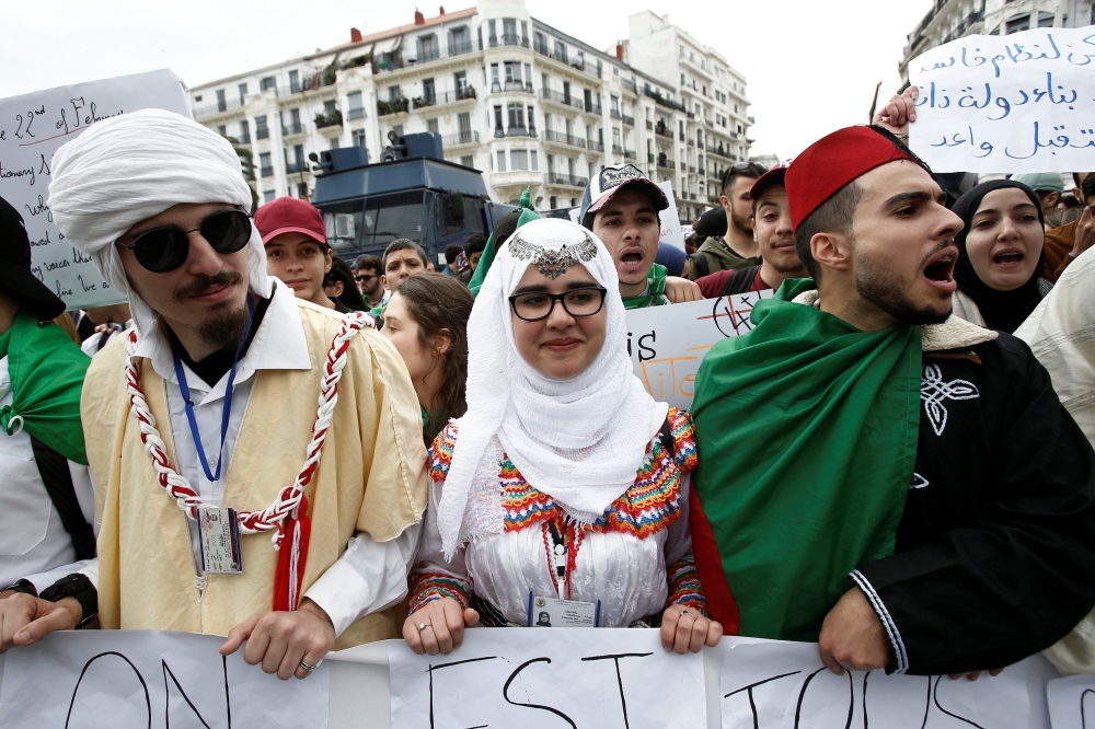 Students wearing traditional clothes hold banners and shout slogans during a protest calling on President Abdelaziz Bouteflika to quit, in Algiers, Algeria, Tuesday. — Reuters