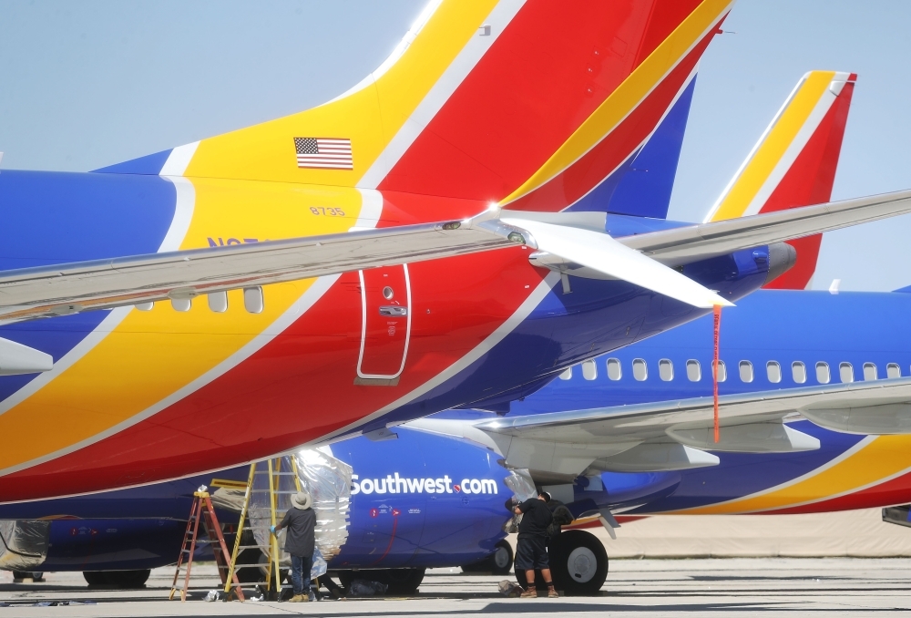 Workers stand beneath Southwest Airlines Boeing 737 MAX aircraft parked at Southern California Logistics Airport in Victorville, California. Southwest Airlines is waiting out a global grounding of MAX 8 and MAX 9 aircraft at the airport. — AFP