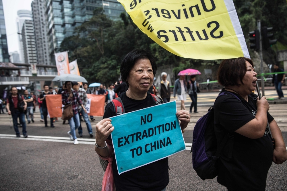 Protesters march along a street during a rally in Hong Kong on Sunday to protest against the government's plans to approve extraditions with mainland China, Taiwan and Macau. — AFP
