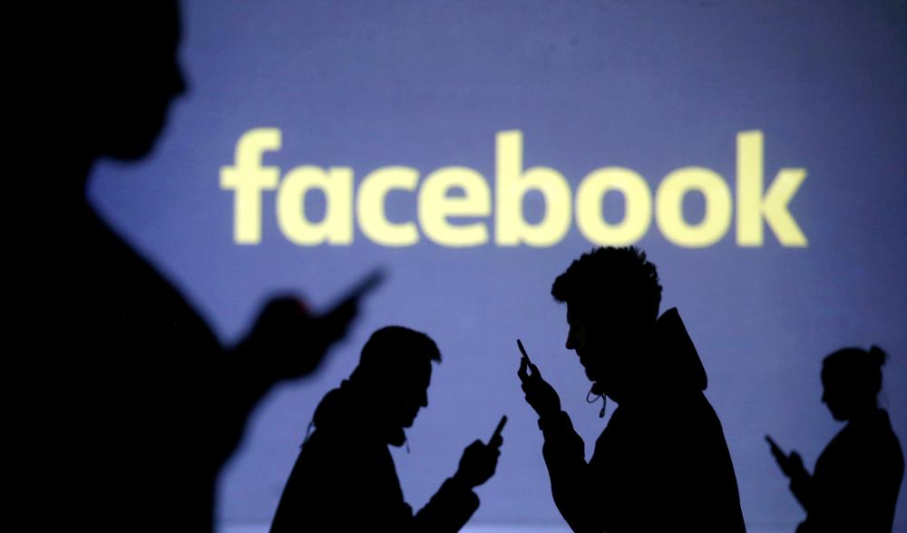 


Silhouettes of mobile users are seen next to a screen projection of Facebook logo in this picture illustration taken on March 28, 2018. — Reuters