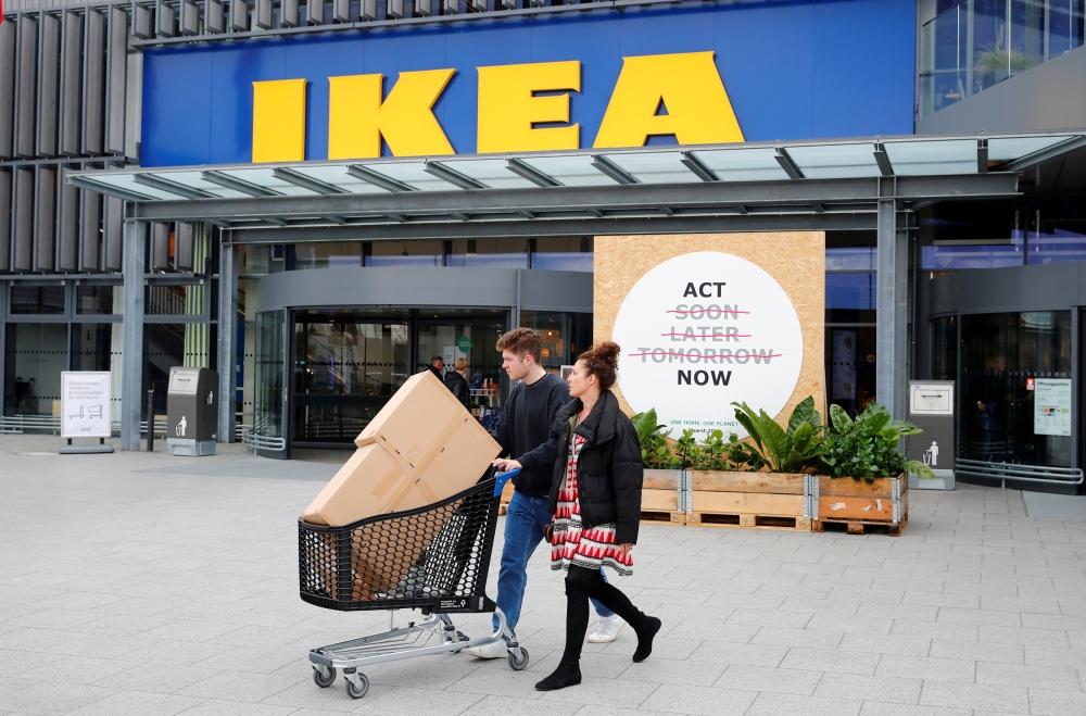 Customers walk by a placard reading “Act Now” as they leave the IKEA store in Kaarst near Duesseldorf, Germany, on Wednesday. — Reuters