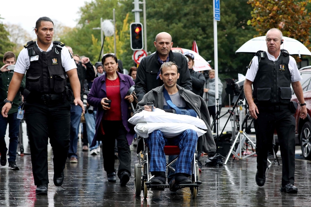 Temel Atacocugu, center, a survivor of the March 15 twin mosque massacre, leaves the Christchurch District Court on Friday after alleged gunman Brenton Tarrant, accused of shooting dead 50 Muslims during the March 15 attack on two mosques, appeared for his hearing via audio-visual link from a maximum-security prison in Auckland. — AFP