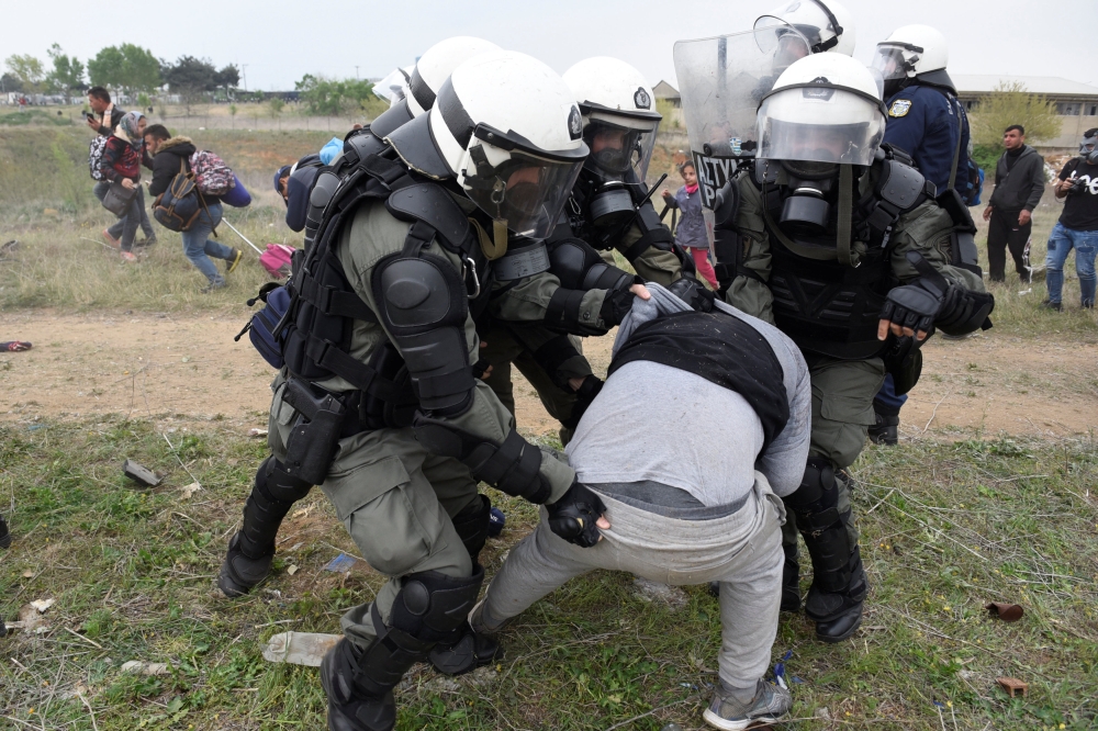 Riot police officers grab a migrant during scuffles, as migrants and refugees, who say that they seek to travel onward to northern Europe, gather outside a camp in the town of Diavata in northern Greece, Saturday. — Reuters