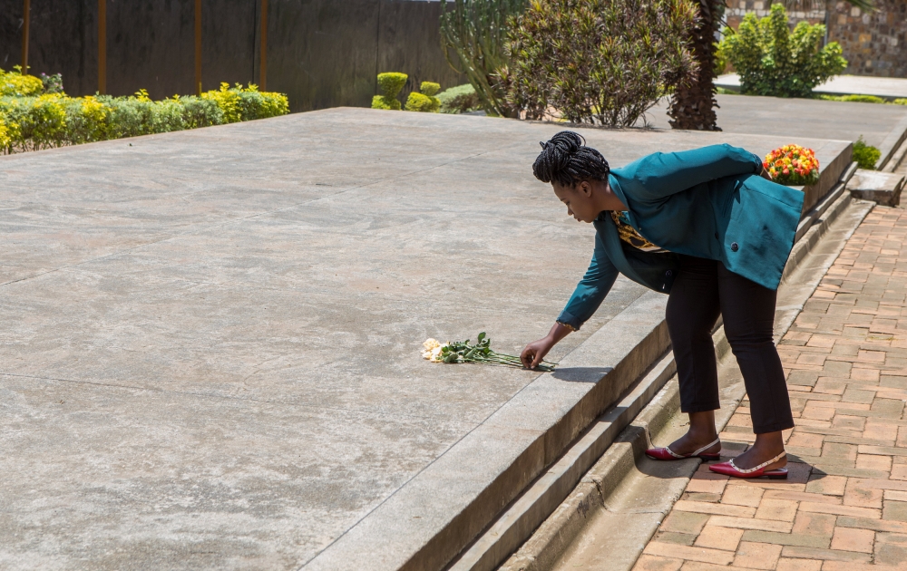 Aline Uwase, a Rwandan genocide survivor place a flower on a mass grave at the Genocide Memorial