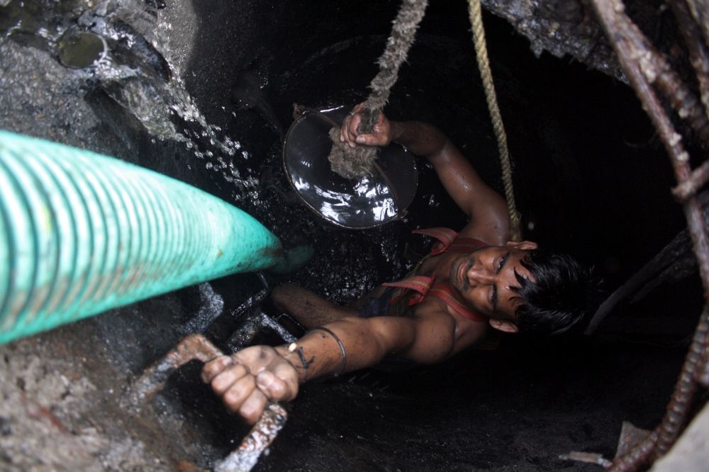 A laborer cleanses an underground sewer at Noida in the northern Indian state of Uttar Pradesh in this file photo. — Reuters