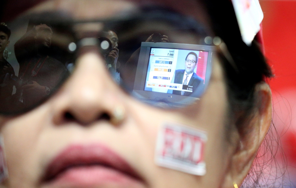 Live results are reflected in glasses of a supporter of Pheu Thai Party during the general election in Bangkok, Thailand. — Reuters