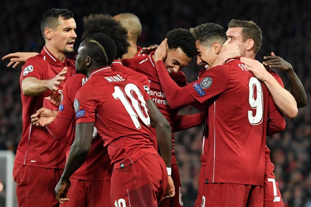 Liverpool’s midfielder Roberto Firmino (R) celebrates with teammates after scoring a goal during the UEFA Champions League quarterfinal first leg match against FC Porto at Anfield Stadium in Liverpool Tuesday. — AFP