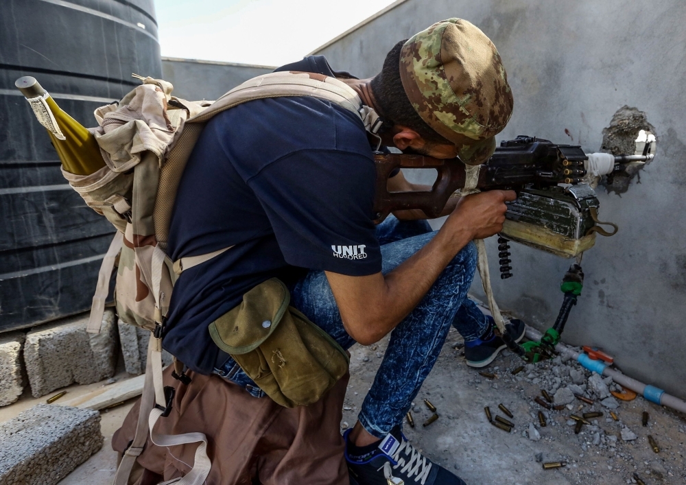 A fighter aims a machine gun through a murder hole at a position held by forces loyal to Libya’s Government of National Accord (GNA) in the suburb of Wadi Rabie about 30 km south of the capital Tripoli on Friday. — AFP