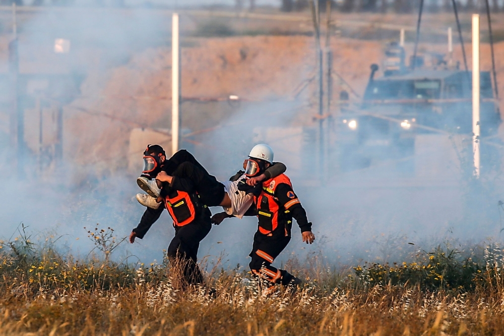 Palestinian paramedics carry an injured protester during a demonstration near the border with Israel, east of Khan Yunis in the southern Gaza Strip, on Friday. — AFP