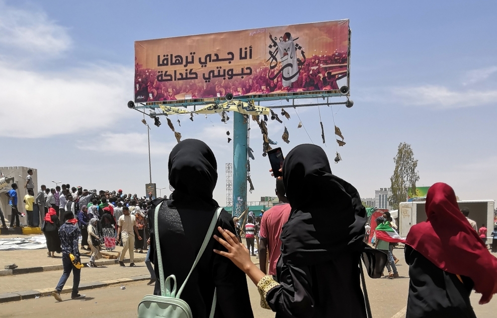 A woman takes a photograph with her smarphone of a billboard showing a reproduction of a picture of Alaa Salah, a Sudanese woman who has become an icon of the protest movement after a video of her leading demonstrators' chants went viral, in the capital Khartoum. — AFP