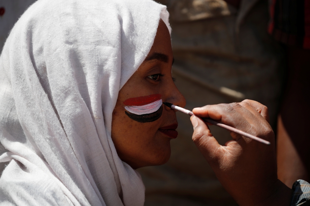 A man paints the Sudanese flag on a demonstrator's face in Khartoum, Sudan, Tuesday. — Reuters