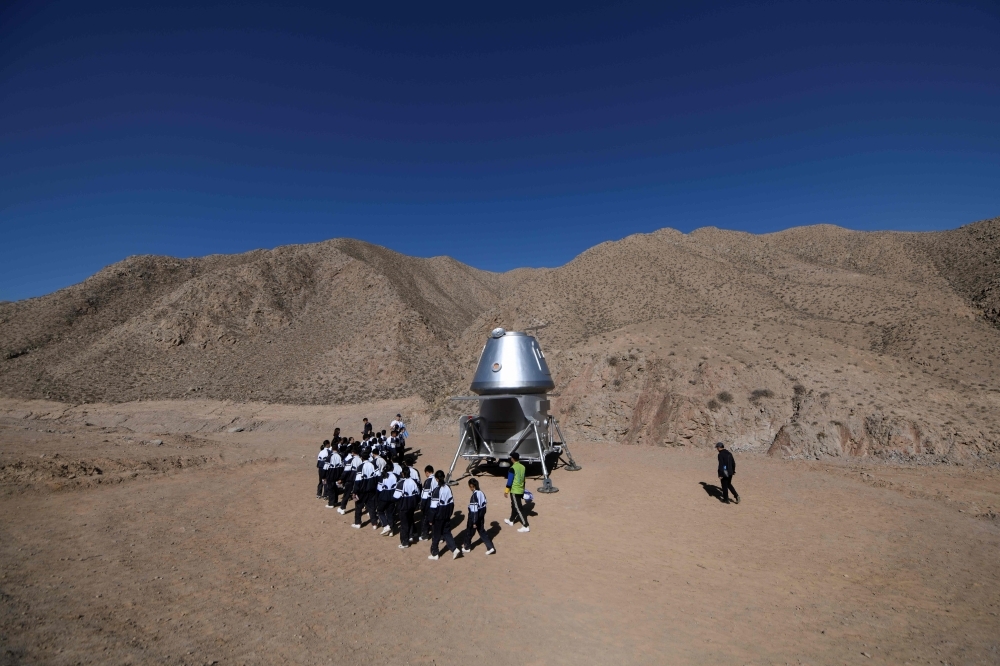 A group of students walk past a model of a lander at 