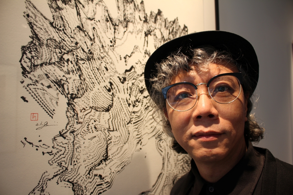 Hong Kong artist Victor Wong stands next to an artwork from his exhibition 'Far Side of the Moon' at 3812 Gallery in London. — Reuters