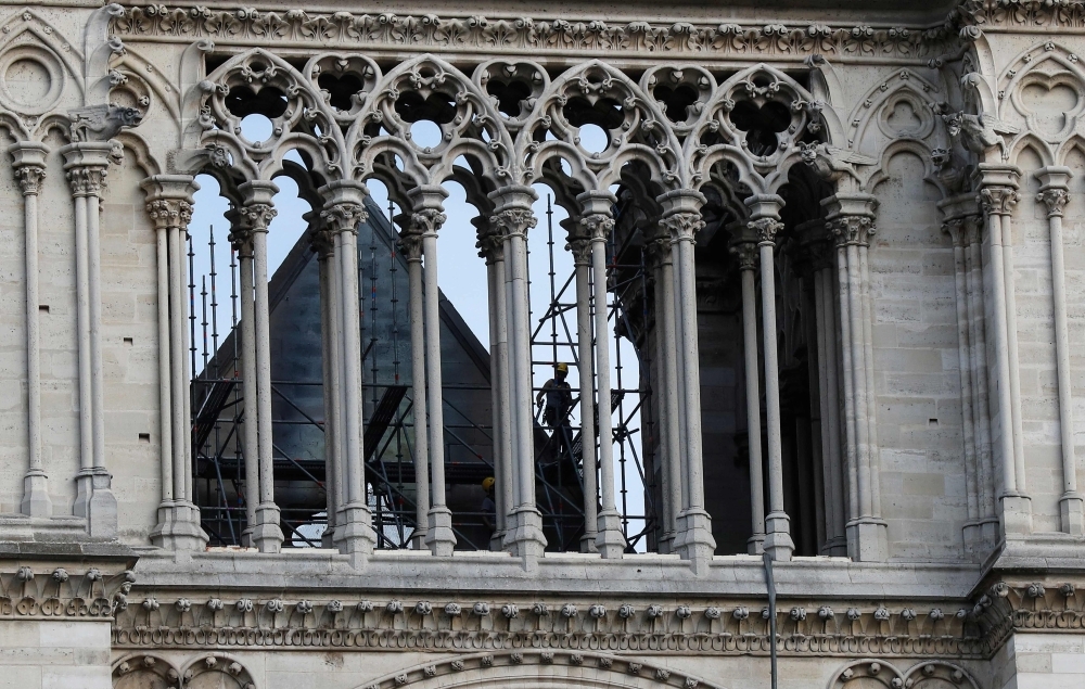 A man works on a scaffold at Notre Dame cathedral on Thursday in Paris. France paid a daylong tribute to the Paris firefighters who saved Notre Dame Cathedral from collapse, while construction workers rushed to secure an area above one of the church's famed rose-shaped windows and other vulnerable sections of the fire-damaged landmark. — AFP