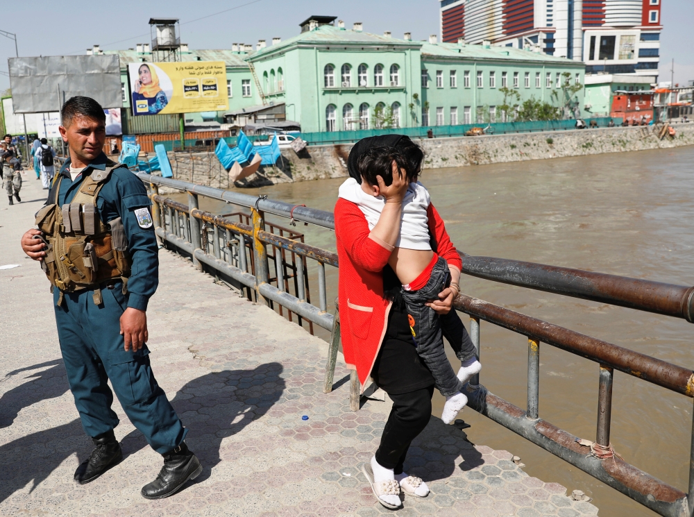An Afghan woman carries a child rescued from the building of Ministry of Communication and Information Technology in Kabul on Saturday. — Reuters