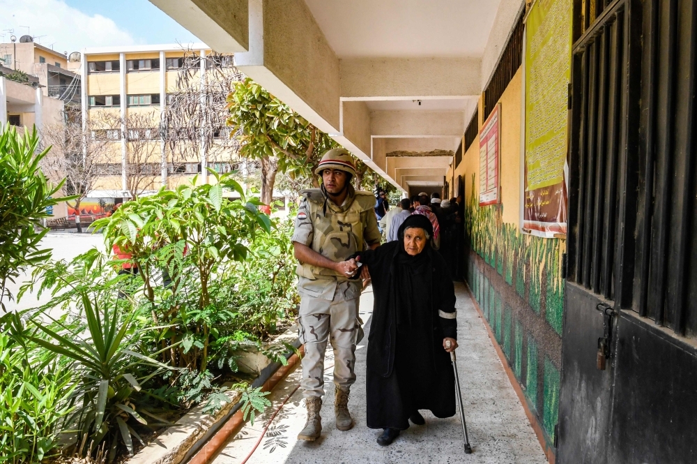 An Egyptian soldier helps an elderly woman to a polling station as she arrives to vote in a referendum on constitutional amendments, at a school in the capital Cairo's northern neighborhood of Shubra, on the first day of a three-day poll, on Saturday.  — AFP