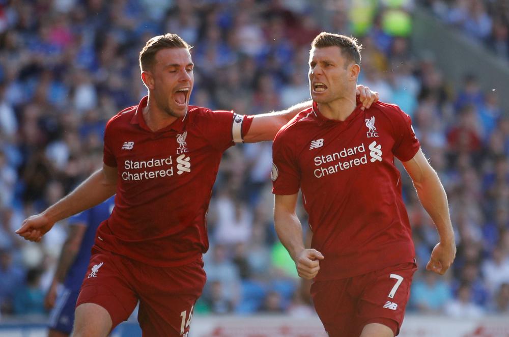 James Milner of Liverpool celebrates scoring their second goal with Jordan Henderson during their Premier League match against Cardiff City in Cardiff Sunday. — Reuters      
