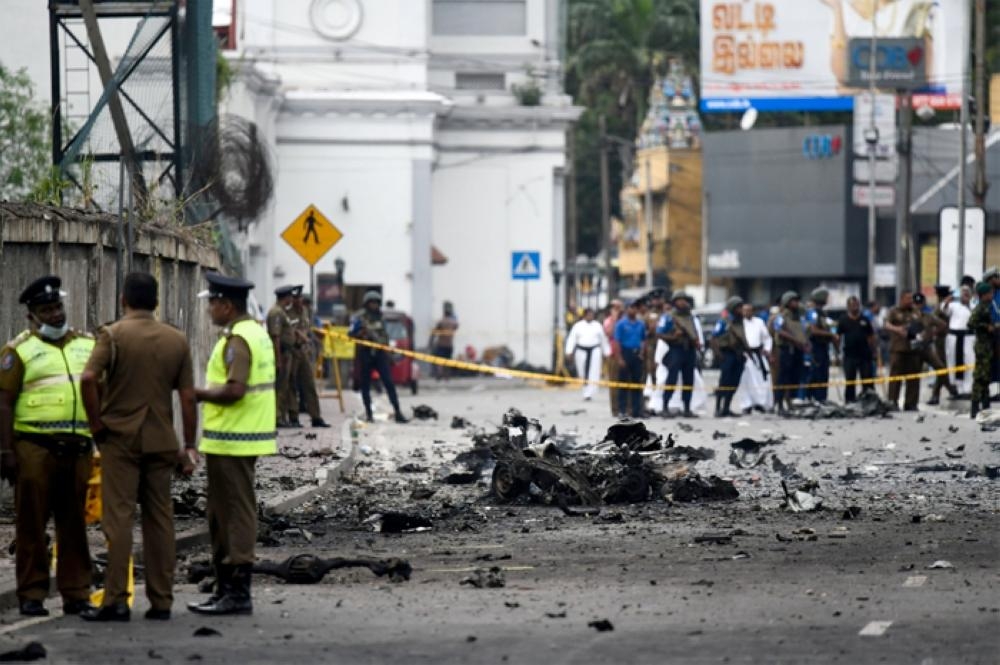 Sri Lankan security personnel inspect the debris of a car after it explodes when police tried to defuse a bomb near St. Anthony's Shrine in Colombo on Sunday. — AFP