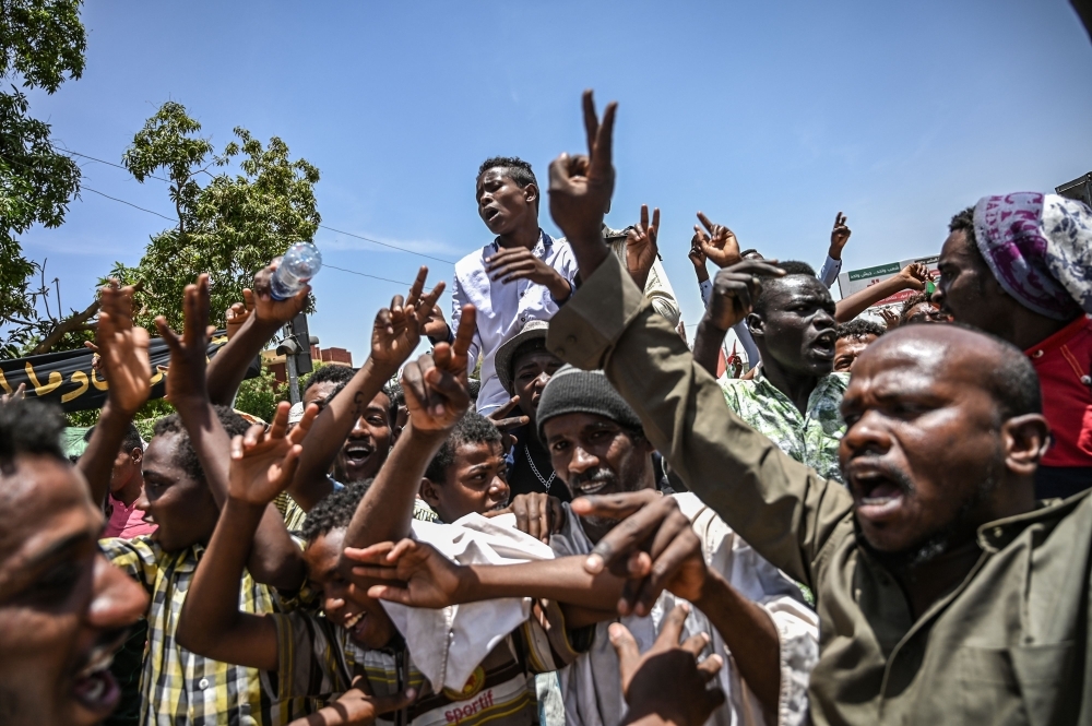 Sudanese protesters shout slogans and flash the victory gesture during a protest outside the army headquarters in the capital Khartoum on Monday. — AFP
