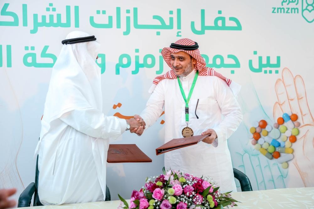Representatives of the Zmzm Association and Nahdi Medical Company exchange documents after signing the agreement.