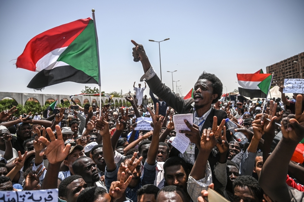 Sudanese protesters wave national flags as they chant slogans during an a sit-in outside the army headquarters in the capital Khartoum on Friday. — AFP
