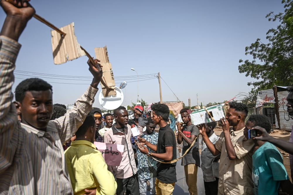 A group of Sudanese boys interview protesters with a fake camera and microphone acting like journalists during an a sit-in outside the army headquarters in the capital Khartoum on Saturday.  — AFP