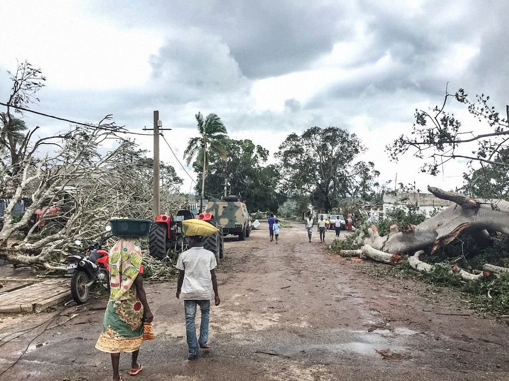 Residents walk past Macomia's heavily defended government quarter where two mature Baobab trees fell on Sunday during Cyclone Kenneth destroying the pavement. — AFP 