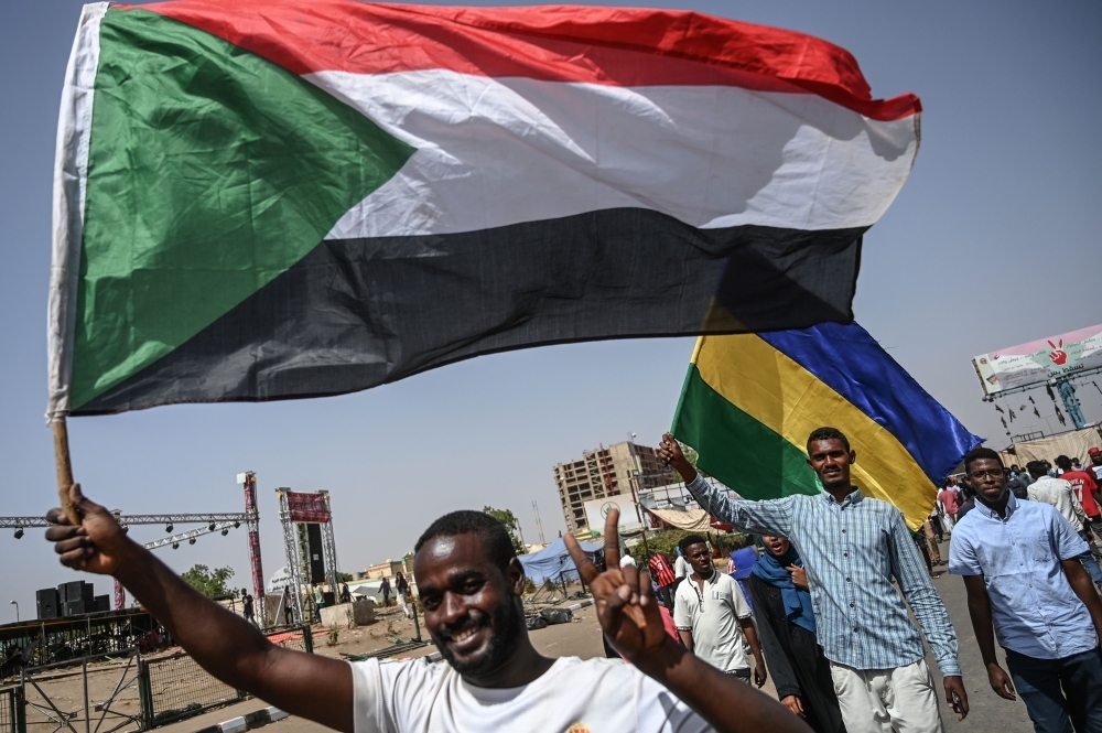 Sudanese protesters wave the current and former national flags during a rally outside the army headquarters in the capital Khartoum. — AFP
