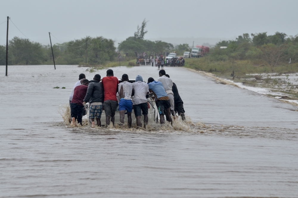 Residents push a car through the floods in Mazive, southern Mozambique, on Sunday. — AFP