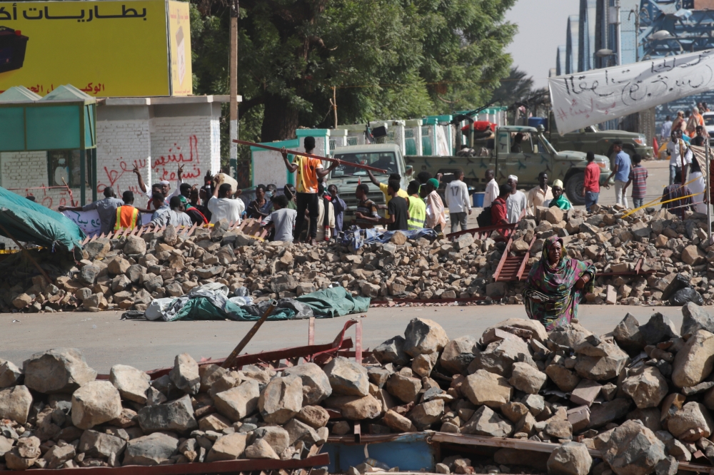 Sudanese protesters walk between barricades on a road leading to the defense ministry compound in Khartoum on Tuesday. — Reuters