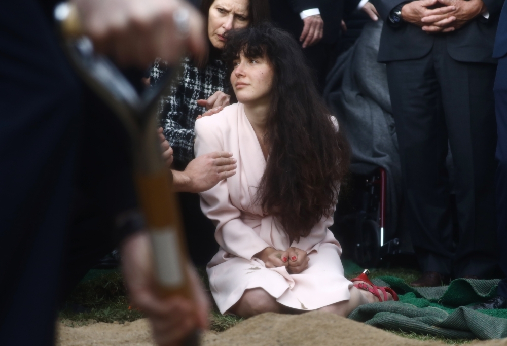 Hannah Kaye, center, daughter of shooting victim Lori Gilbert Kaye, mourns at her mother’s grave during a graveside service in San Diego, California, on Monday. — AFP