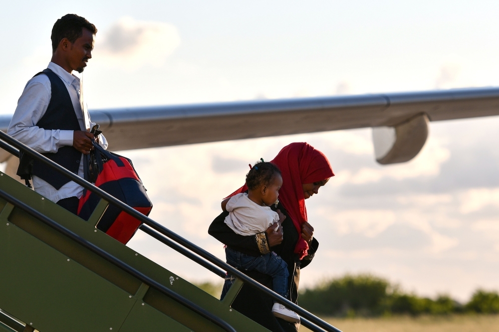 A woman carries a child as she disembarks with a man from an aircraft at Pratica di Mare Airport, on the outskirts of Rome on Monday, among some 147 refugees from Eritrea, Somalia, Syria, Sudan and Ethiopia who have been evacuated from the Libyan city of Misrata. — AFP