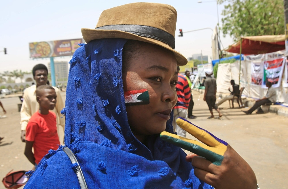 A Sudanese protester with the national flag of Sudan painted on her face, flashes the victory sign during a sit-in outside the army headquarters in the capital Khartoum on Wednesday. — AFP