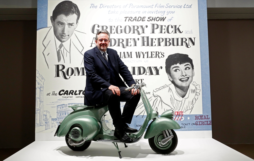 Audrey Hepburn’s son, Sean Hepburn Ferrer, poses on the Vespa scooter his mother rode on in the 1953 movie “Roman Holiday” at the exhibition “Intimate Audrey” in Brussels, Belgium, on Thursday. — Reuters