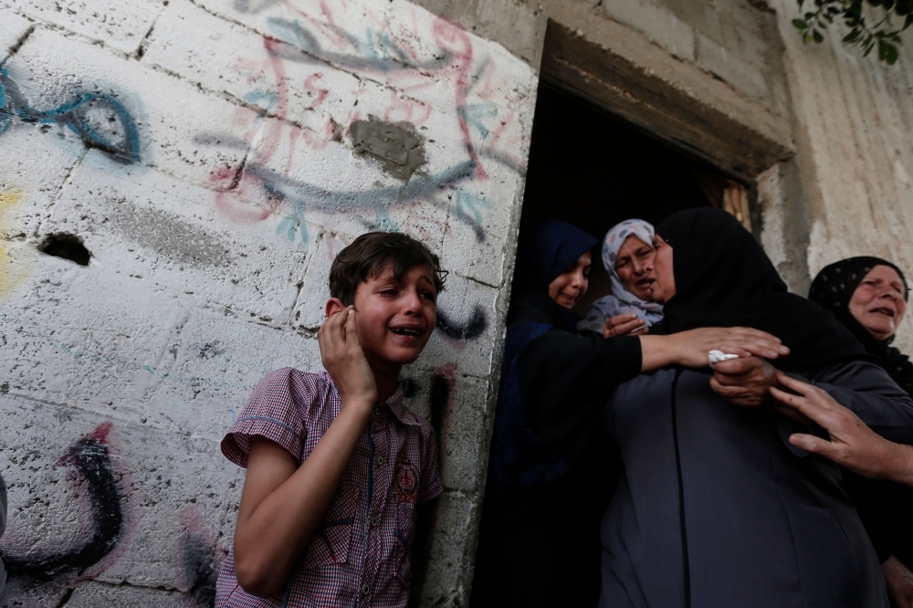 Relatives mourn during the funeral of five Palestinians, who were killed in Israeli strikes the previous day, in Beit Lahia, in northern Gaza strip on Monday. — AFP
