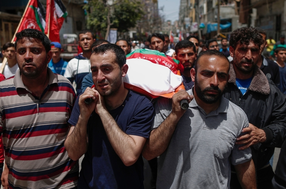 Relatives mourn during the funeral of five Palestinians, who were killed in Israeli strikes the previous day, in Beit Lahia, in northern Gaza strip on Monday. — AFP
