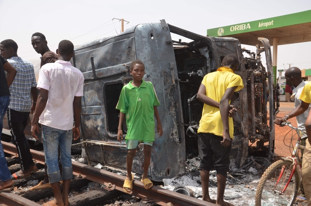 Residents look at a calcined tanker truck after an explosion which killed more than 55 people near the airport of Niamey on Monday. — AFP