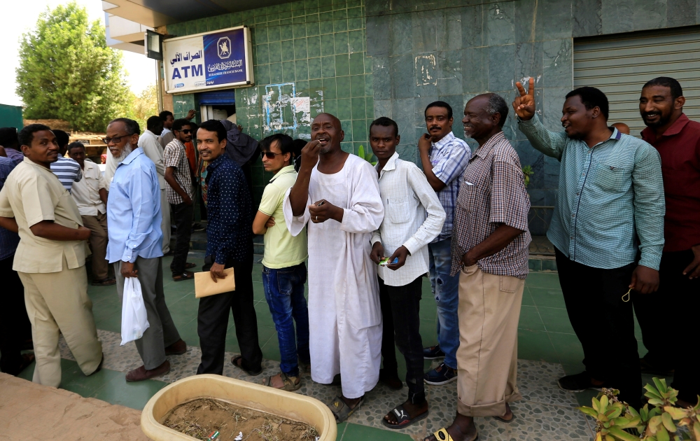 People queue to withdraw money from an automated teller machine, ATM, in Khartoum, Sudan, on Tuesday. — Reuters