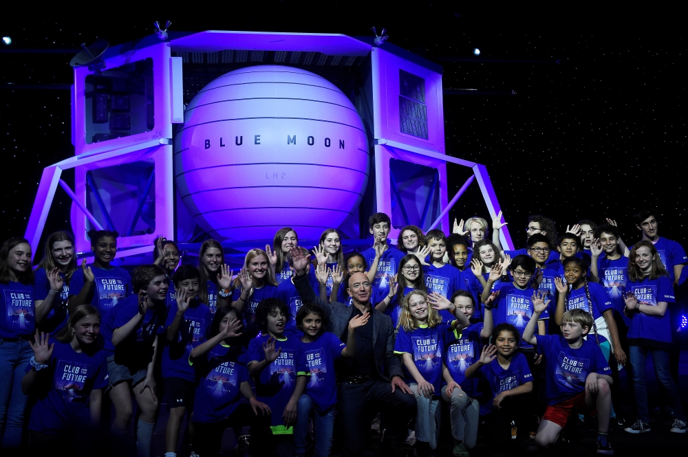 Amazon chief Jeff Bezos poses with children after his space company Blue Origin’s space exploration lunar lander rocket called Blue Moon was unveiled at an event in Washington on Thursday. — Reuters