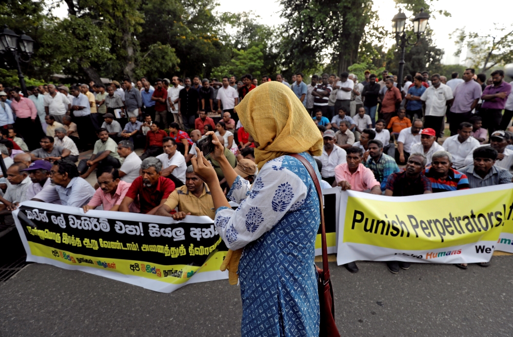 A Muslim girl takes pictures during a protest against the mob attacks against Muslims in few villages after Easter Sunday bomb attacks by militants in Colombo, Sri Lanka, on Thursday. — Reuters