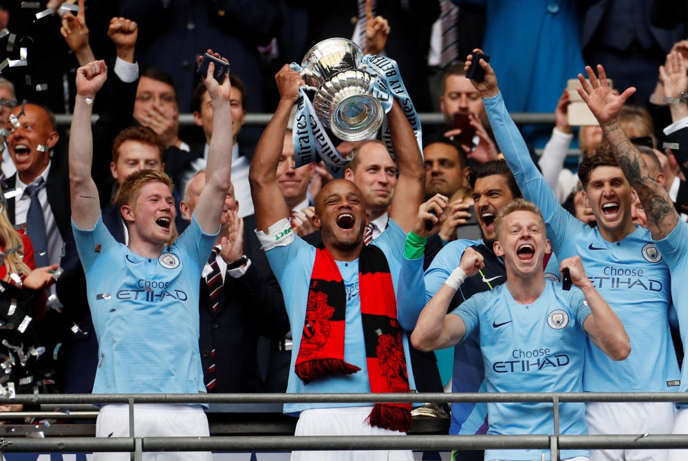Manchester City’s Vincent Kompany lifts the trophy as they celebrate after winning the FA Cup at Wembley Stadium in London on Saturday. — Reuters