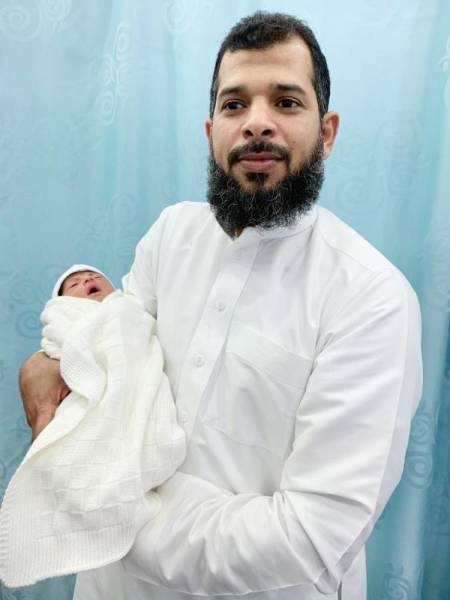 Abdul Rahman Farie is holding his brother's newborn daughter Noor, after she was returned to the family following the kidnap incident.