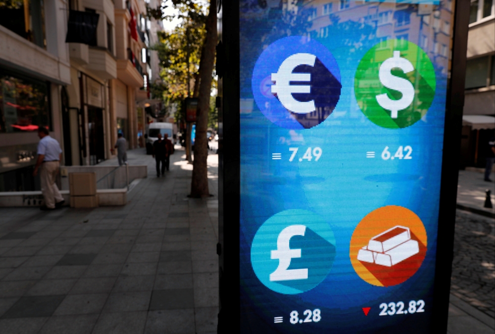 Pedestrians walk past an electronic board showing the currency exchange rates in Istanbul in this Aug. 31, 2018, file photo. — Reuters