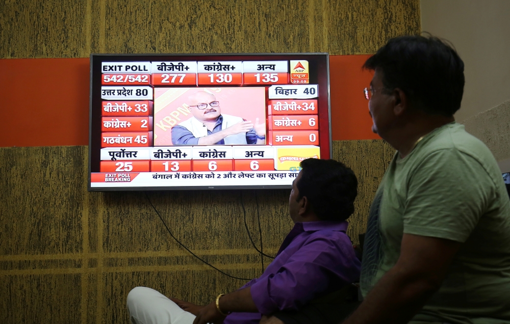 Men look at a television screen showing exit poll results after the last phase of the general election in Ahmedabad, India, May 19. - Reuters