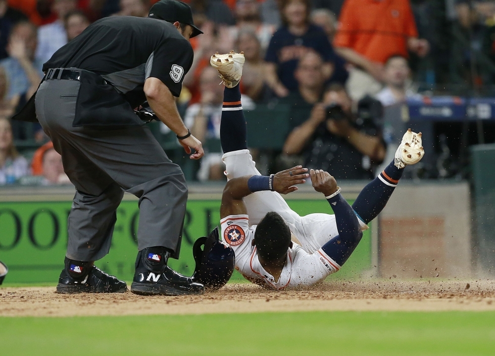 Tony Kemp No.18 of the Houston Astros scores on a wild pitch in the fifth inning as he gets tangled up with home plate umpire Mark Ripperger at Minute Maid Park  in Houston, Texas on Tuesday. — AFP